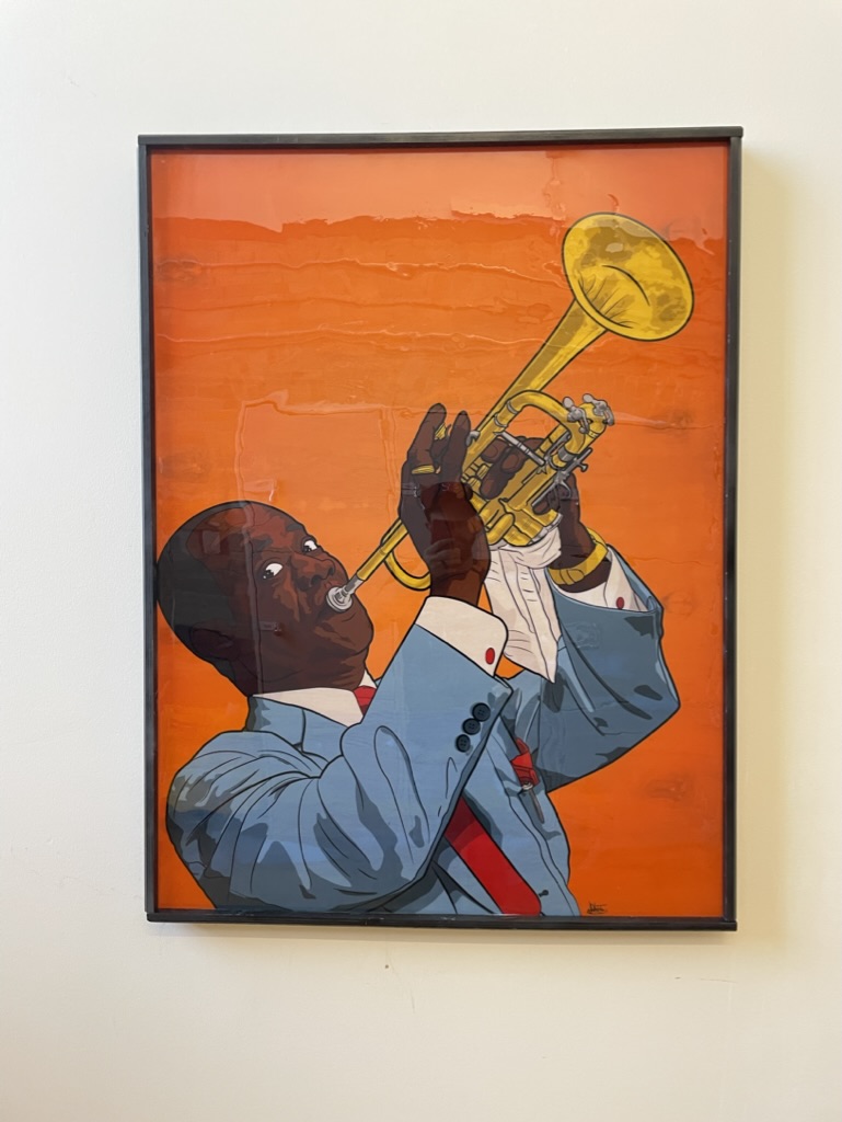 A printed and framed poster of an colorful illustrated poster of jazz trumpeter and singer Louis Armstrong