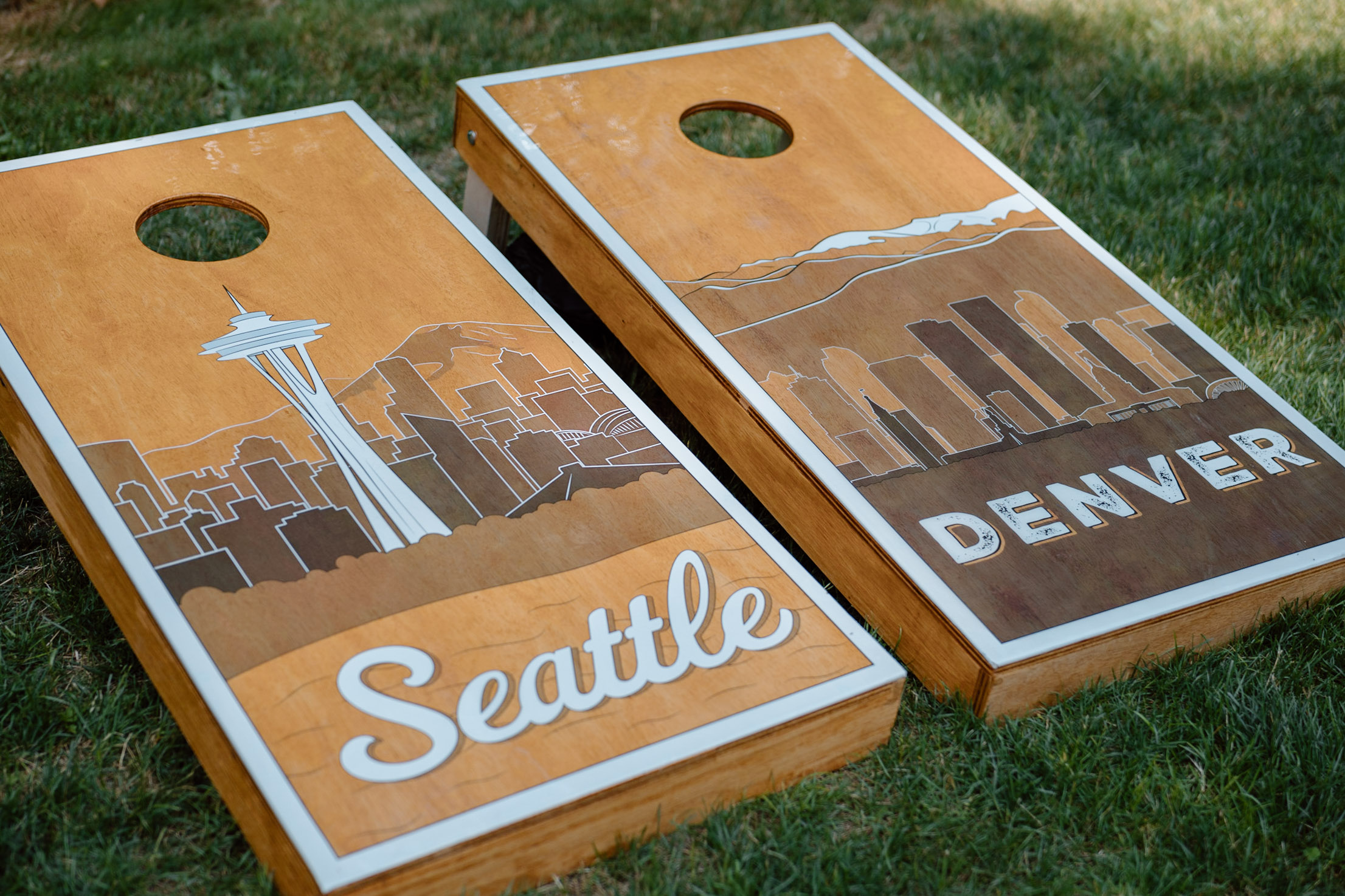 Full set of custom cornhole boards with a illustrated and stylized skylines of Seattle and Denver.