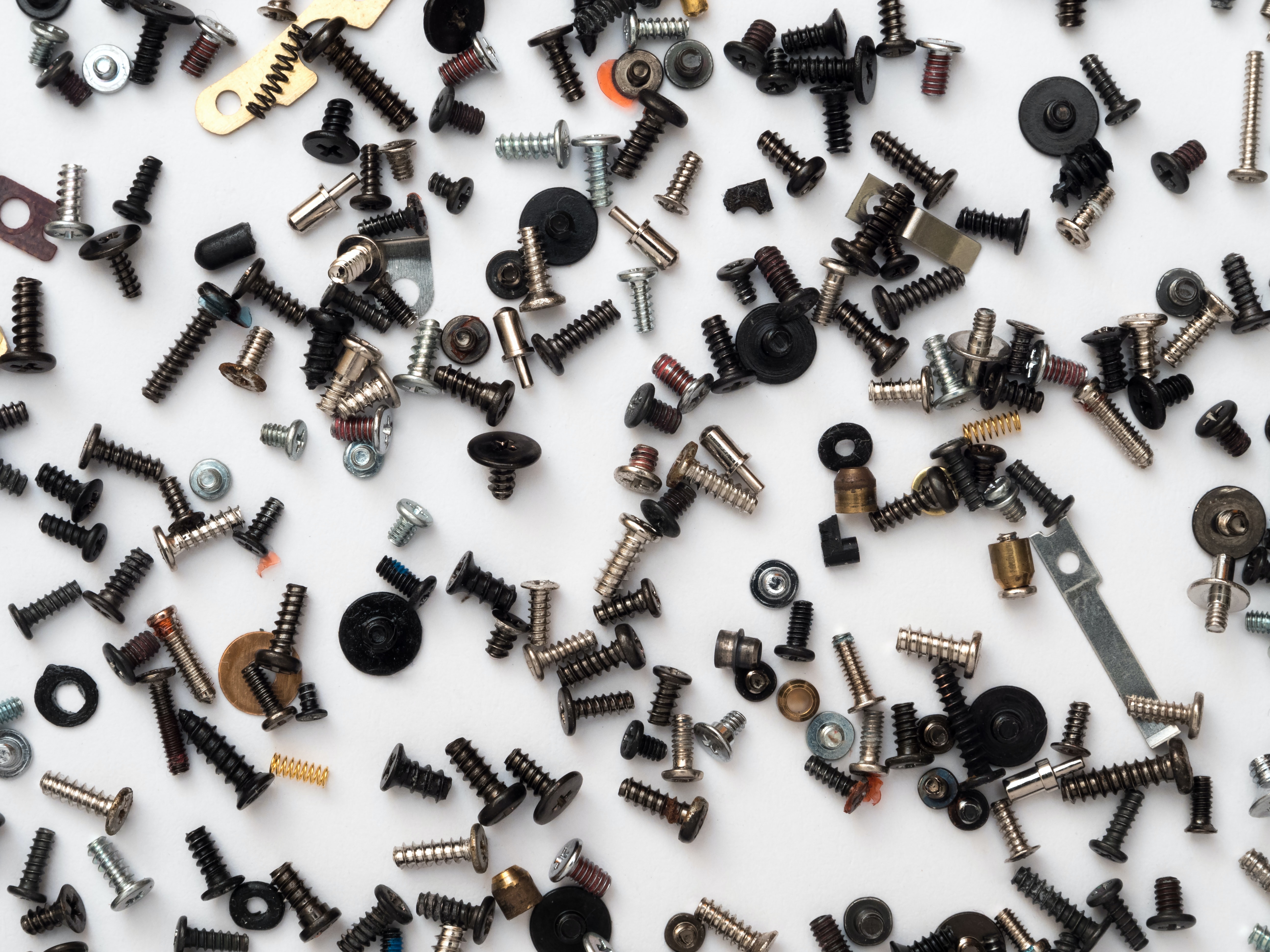 An image of small parts like screws, nuts and bolts strewn accross a white background.