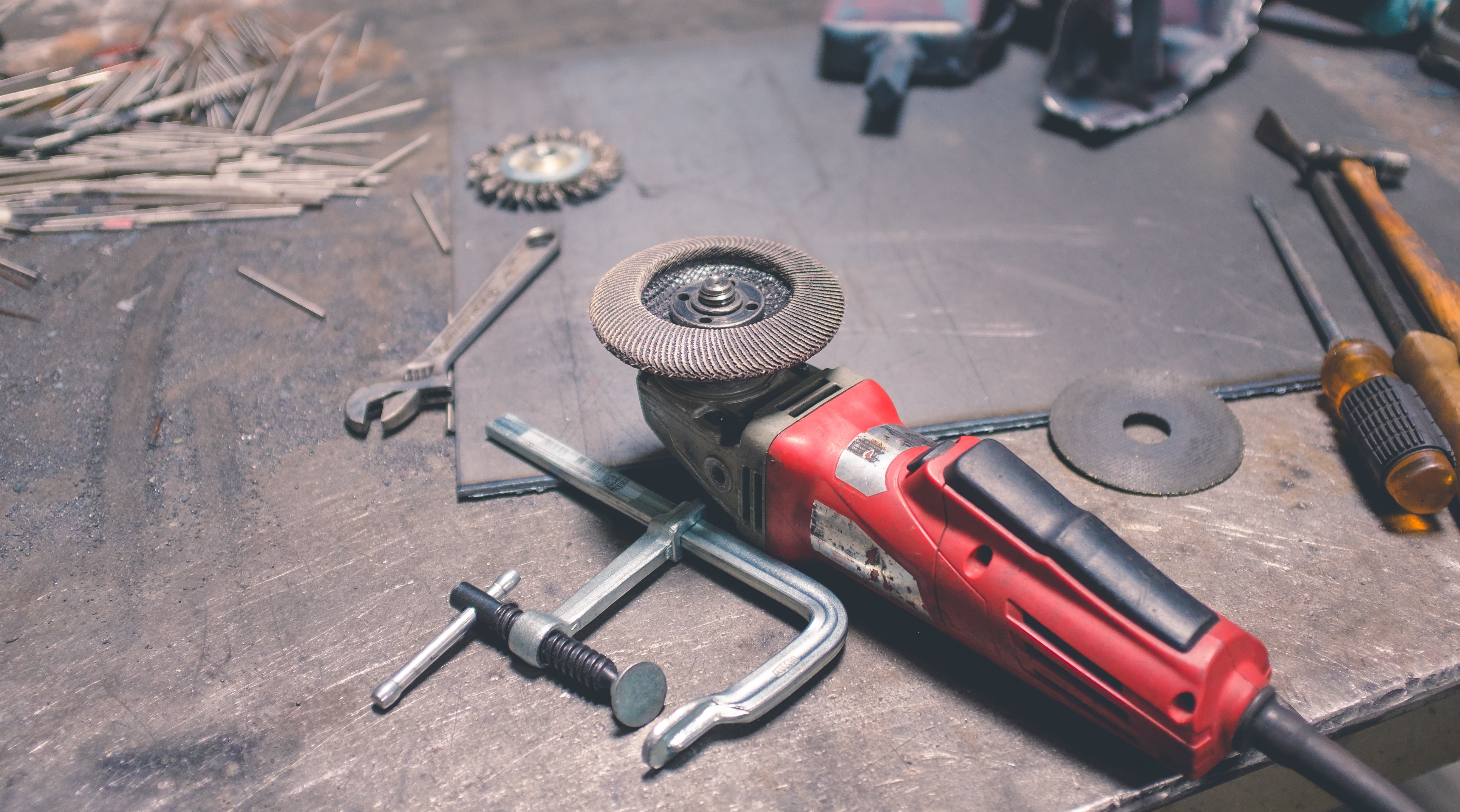 An angle grinder and clamp among other tools sitting on a workbench